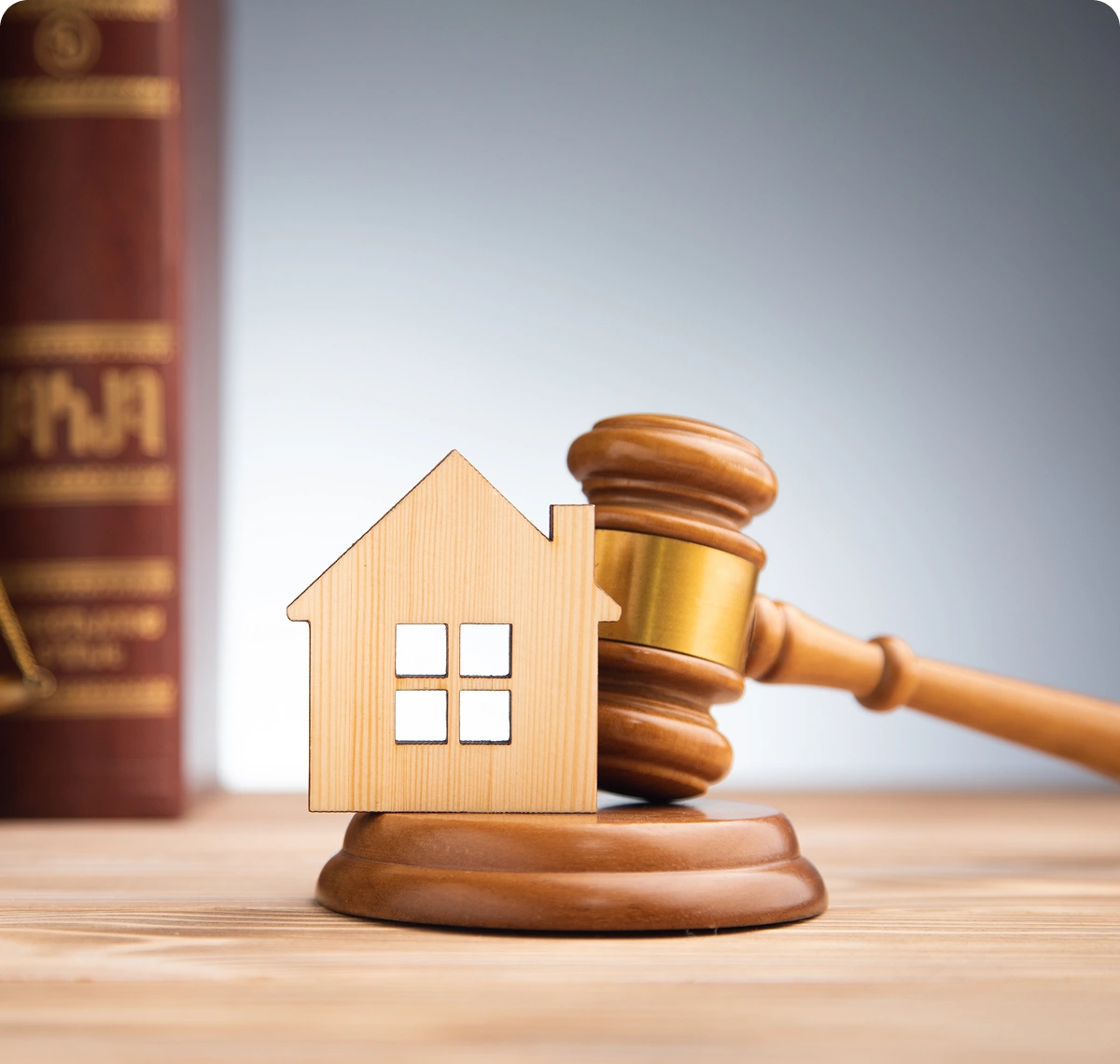 Miniature wooden house model sitting on top of a gavel.
